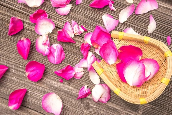 Roze bloemblaadjes van roos op oude plank — Stockfoto