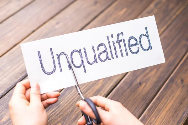 Woman holds white paper with word unqualified — Stock Photo, Image