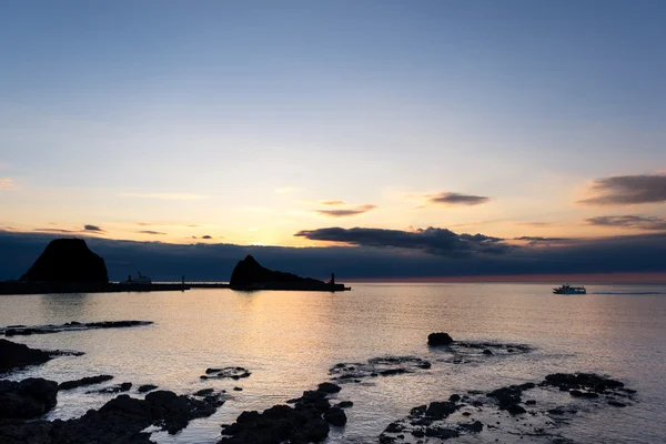 Praia de rocha perto do mar tranquilo ao nascer do sol — Fotografia de Stock
