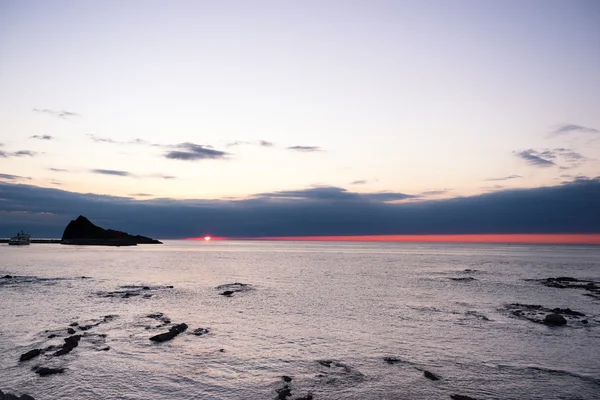 Praia de rocha perto do mar tranquilo ao nascer do sol — Fotografia de Stock