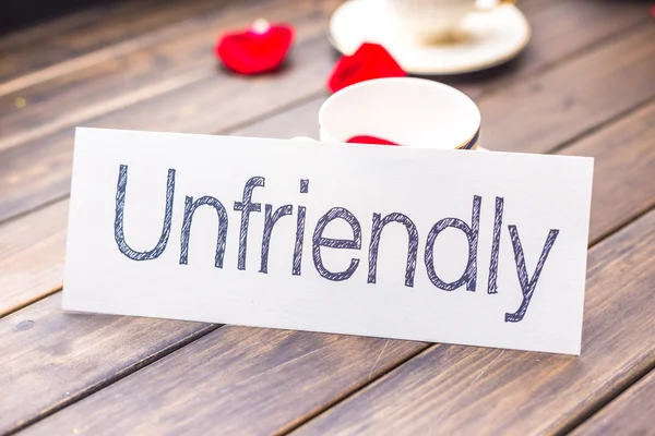 Paper with word unfriendly against coffee cup — Stock Photo, Image