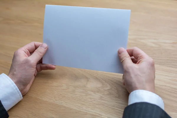 Empresário segurando papel branco em branco — Fotografia de Stock