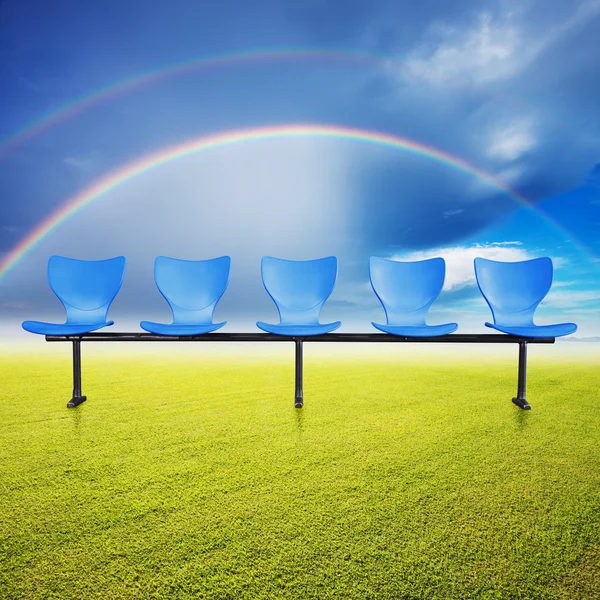 Chairs over the grass filed and rainbow background — Stock Photo, Image