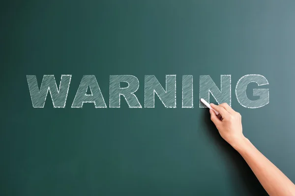 Warning written on blackboard — Stock Photo, Image