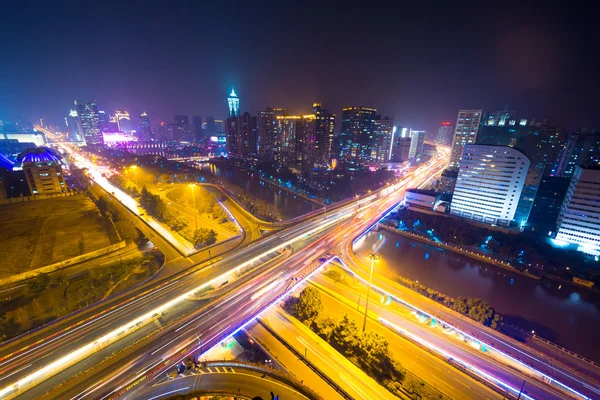 Traffic light trails on overpass and cityscape — Stock Photo, Image