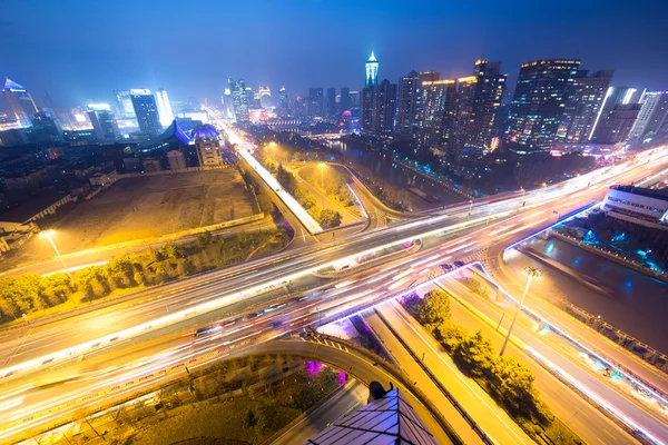 Traffic light trails on overpass and cityscape — Stock Photo, Image