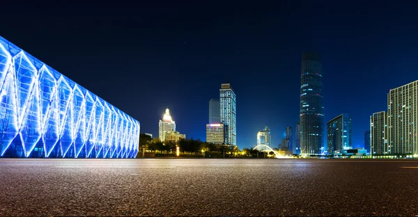 Empty asphalt road and modern skyline at night