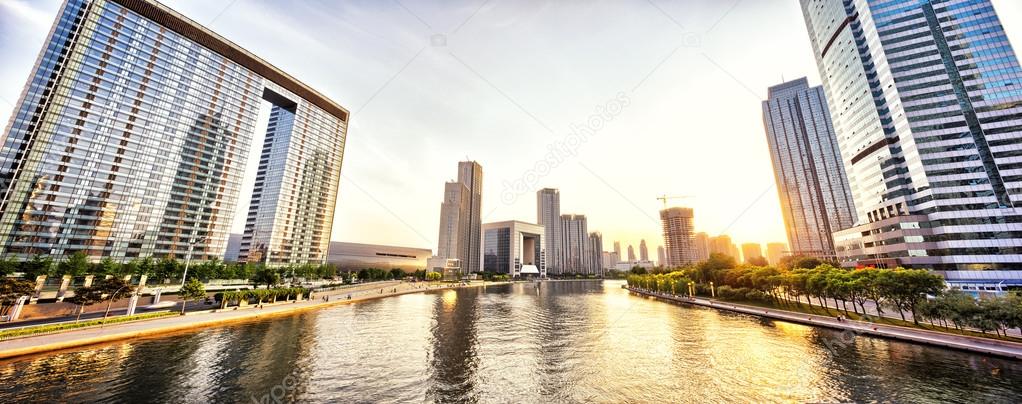 modern skyscrapers and skyline during sunset at riverbank