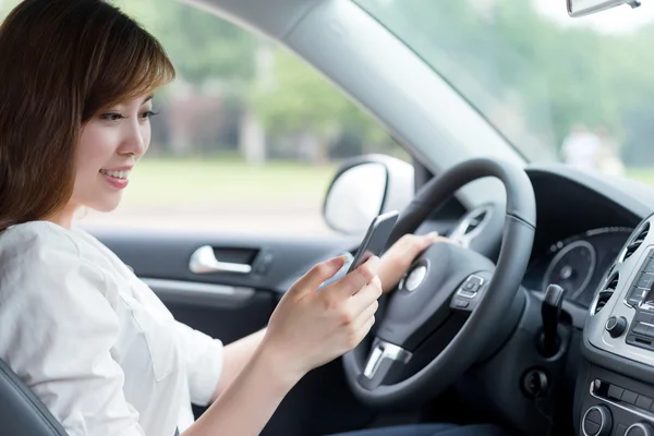 Mulher usando telefone celular e carro de condução — Fotografia de Stock