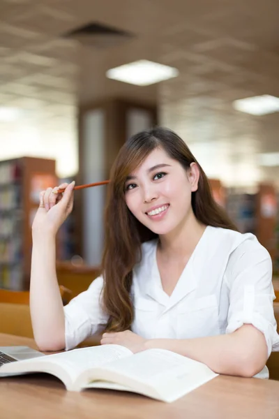 Vrouwelijke student studeren in de bibliotheek met laptop — Stockfoto