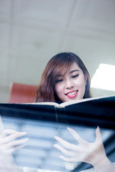 Asiatische Studentin hält Buch in Bibliothek — Stockfoto