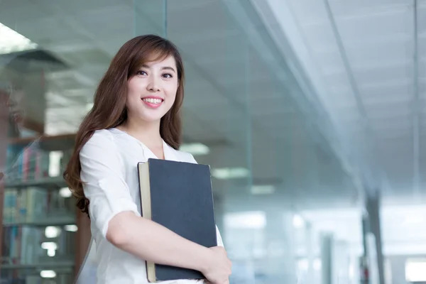 Asiatische Studentin hält Buch in Bibliothek — Stockfoto