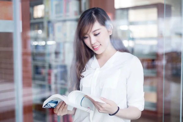 Ασιατικές φοιτήτριας εκμετάλλευση βιβλίο στη βιβλιοθήκη — Φωτογραφία Αρχείου