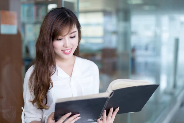 Asiática estudiante sosteniendo libro en biblioteca — Foto de Stock