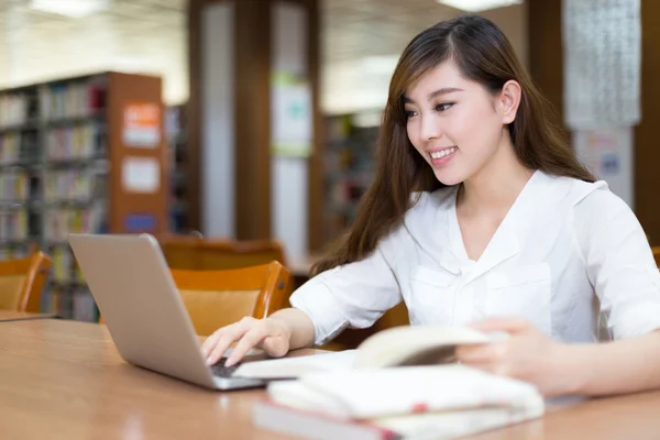Estudante do sexo feminino estudando na biblioteca com laptop — Fotografia de Stock