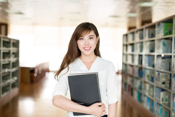 Asiática estudiante sosteniendo libro en biblioteca — Foto de Stock