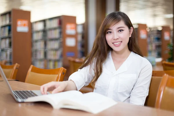 亚洲女学生在图书馆中使用笔记本电脑 — 图库照片