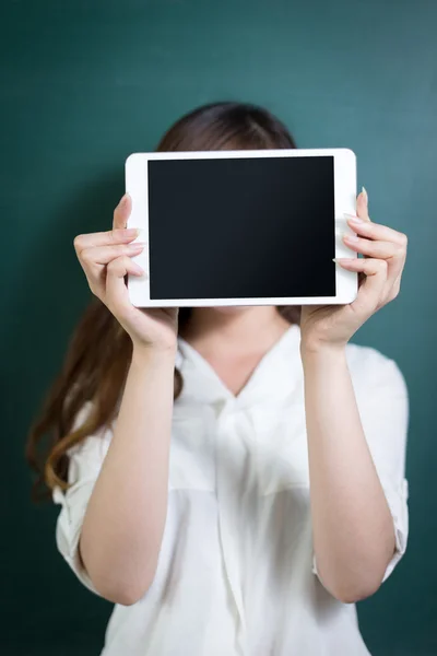 Mujer sosteniendo la tableta delante de la pizarra —  Fotos de Stock