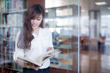 Asyalı kız öğrenci holding kitap kütüphane 