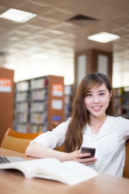 Kız öğrencinin cep telefonuyla Kitaplığı'nda