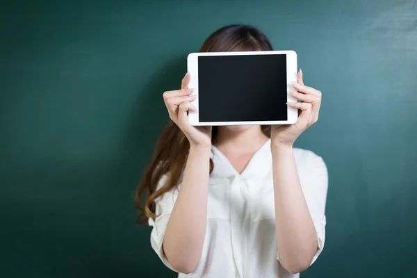 Mujer sosteniendo la tableta delante de la pizarra —  Fotos de Stock
