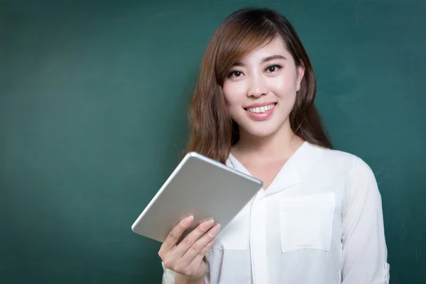 Asiático mulher segurando tablet na frente de blackboard — Fotografia de Stock