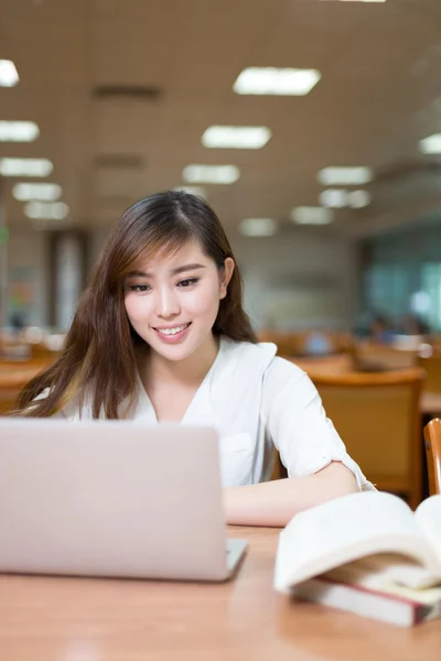 Estudiante que estudia en la biblioteca con portátil — Foto de Stock