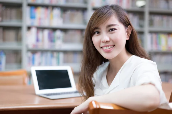Asian female student using laptop in library — Stock Photo, Image