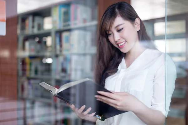 Asiática estudiante sosteniendo libro en biblioteca — Foto de Stock