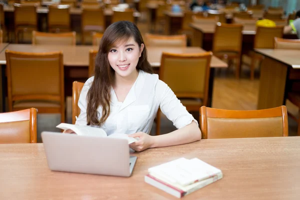 Studente donna che studia in biblioteca con computer portatile — Foto Stock