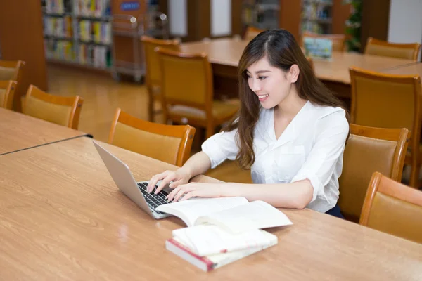Estudante do sexo feminino estudando na biblioteca com laptop — Fotografia de Stock