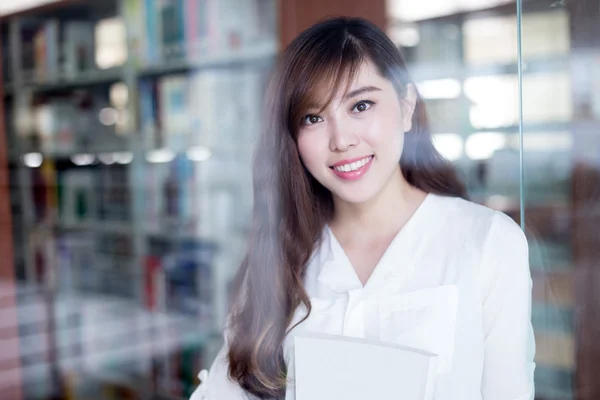 Asijská studentka hospodářství kniha v knihovně — Stock fotografie
