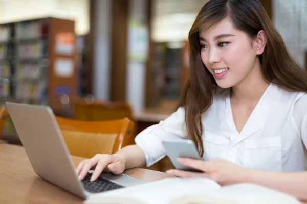 Студентка учится в библиотеке с ноутбуком — стоковое фото