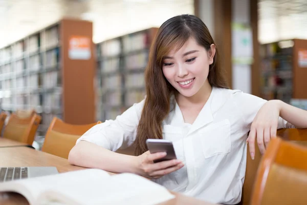 여자 학생 도서관에서 휴대 전화를 사용 하 여 — 스톡 사진