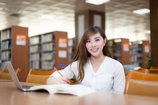 Asiática estudiante usando laptop en biblioteca —  Fotos de Stock