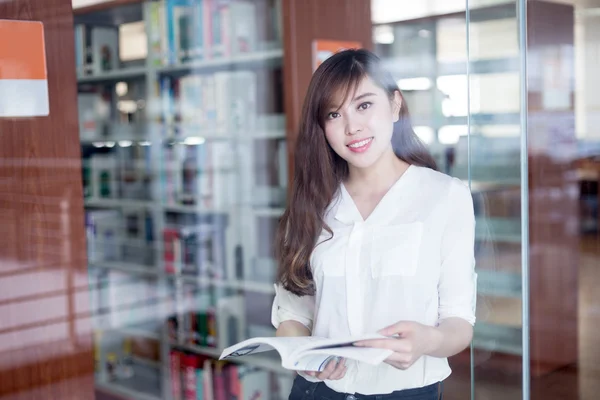 Asyalı kız öğrenci holding kitap kütüphane — Stok fotoğraf