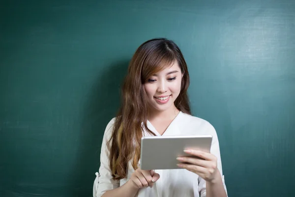 Asiatin hält Tablet vor Tafel — Stockfoto