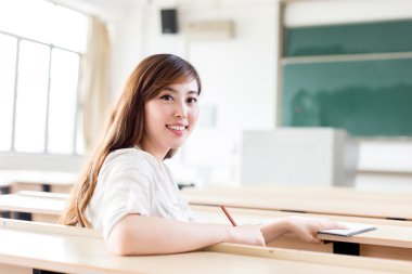 Asyalı kız öğrenci sınıfta okuyor.