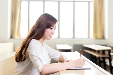 Asyalı kız öğrenci sınıfta okuyor.