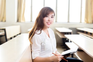 Asyalı kız öğrenci sınıfta okuyor.