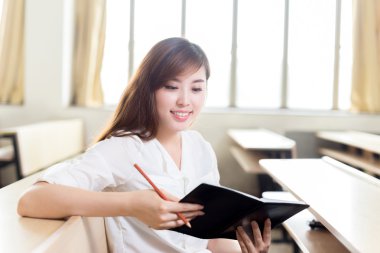 Asyalı kız öğrenci sınıfta okuyor.