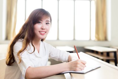 Asyalı kız öğrenci sınıfta okuyor.