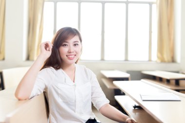 Asyalı kız öğrenci sınıfta okuyor.