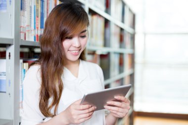 Asyalı kız öğrenci Kitaplığı'nda tablet kullanma