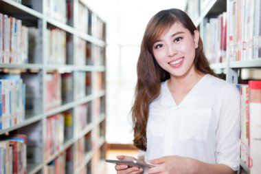 Asyalı kız öğrenci Kitaplığı'nda tablet kullanma