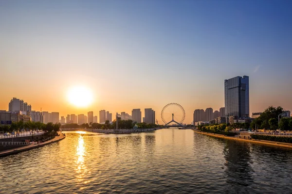 Modern city skyline and buildings at riverbank during sunset — Stock Photo, Image