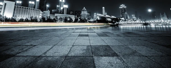 Light trails and cityscape with empty road floor — Stock Photo, Image