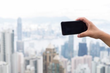 hareket eden telefon ile cityscape arka plan olarak tutan el