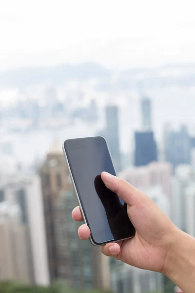 Mano celebración de teléfono móvil con paisaje urbano como fondo —  Fotos de Stock