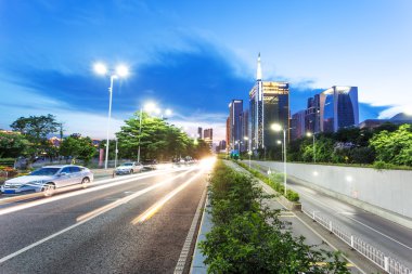 skyscrapers of a modern city at dusk with street lamps clipart